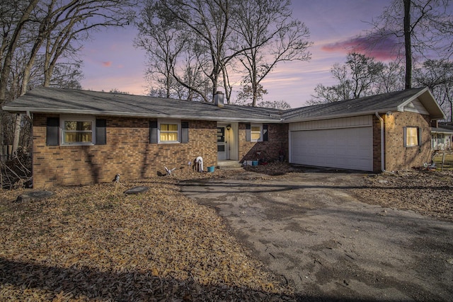 ranch-style house with a garage, aphalt driveway, and brick siding