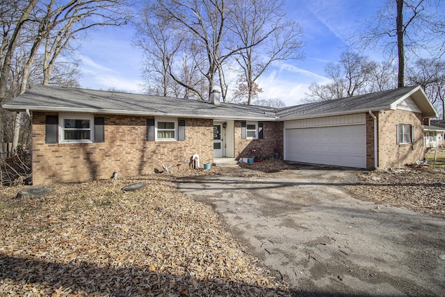 ranch-style home featuring aphalt driveway, brick siding, and a garage