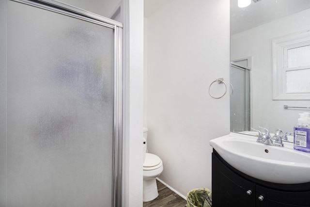 bathroom featuring toilet, a shower stall, wood finished floors, and vanity