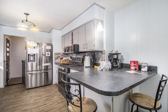 kitchen featuring dark countertops, stainless steel appliances, dark wood-style flooring, and a kitchen breakfast bar