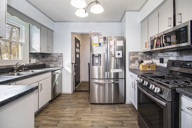 kitchen featuring dark countertops, appliances with stainless steel finishes, dark wood-style flooring, and a sink