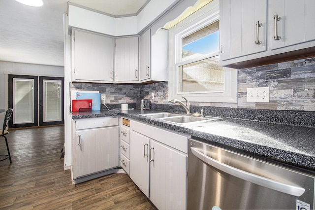 kitchen with dark countertops, a sink, backsplash, and stainless steel dishwasher