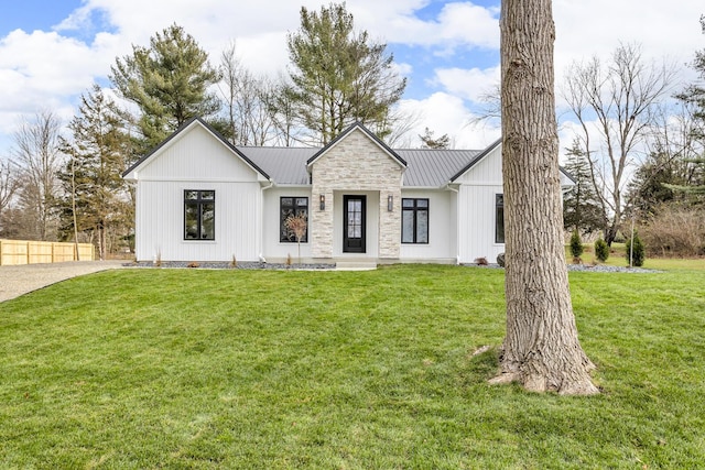 modern farmhouse with metal roof, a front lawn, and fence