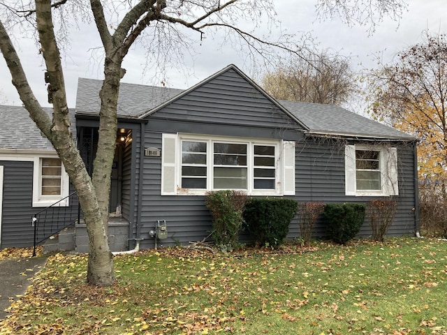 view of front of home with a shingled roof and a front yard