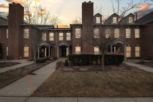 view of front facade with brick siding and a chimney