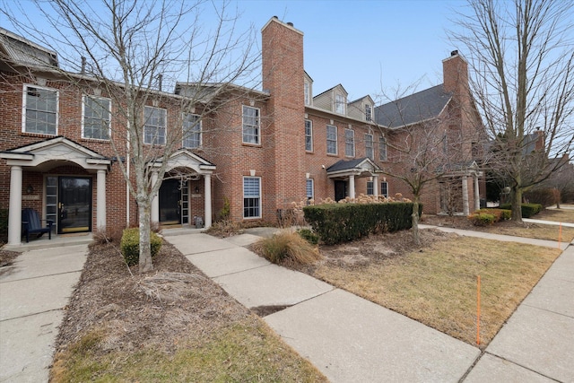 view of front of home with brick siding and a chimney