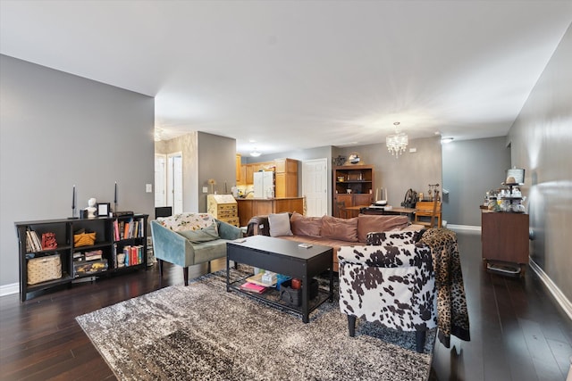 living room with dark wood-style floors, baseboards, and an inviting chandelier