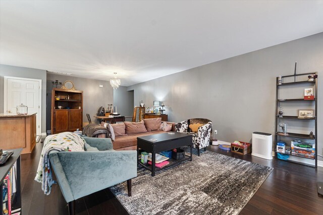 living area with dark wood-style floors, baseboards, and an inviting chandelier