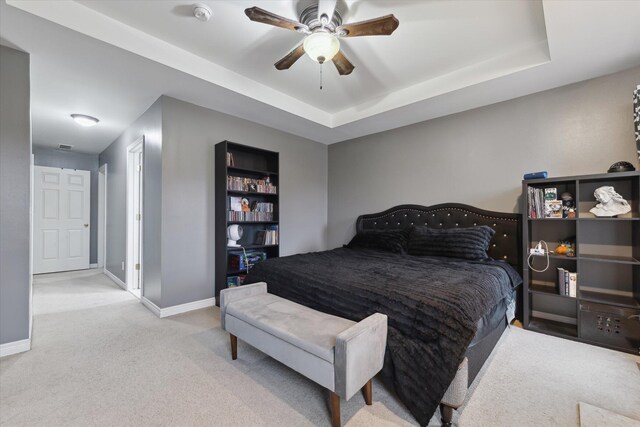 bedroom with a ceiling fan, baseboards, a tray ceiling, and carpet flooring