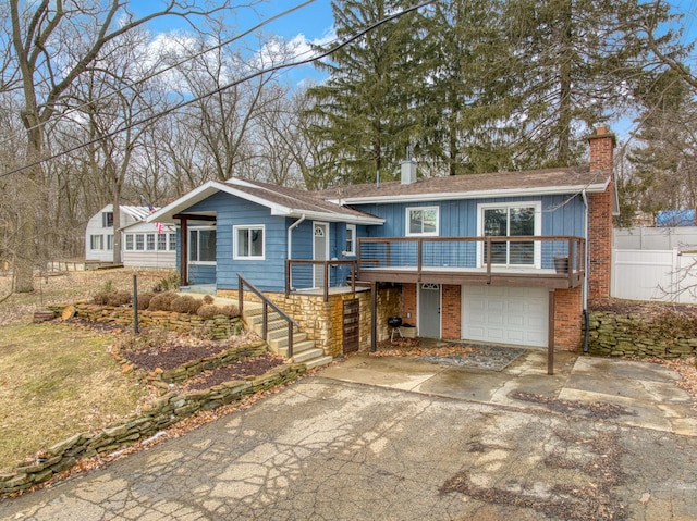 split level home with a garage, brick siding, stairs, driveway, and a chimney