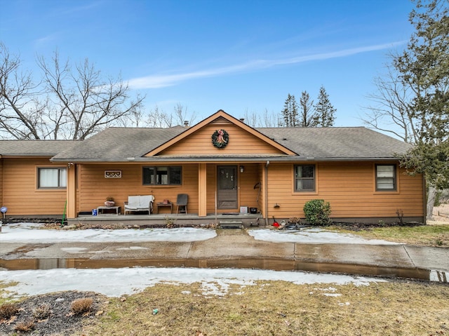 chalet / cabin featuring a porch and a shingled roof