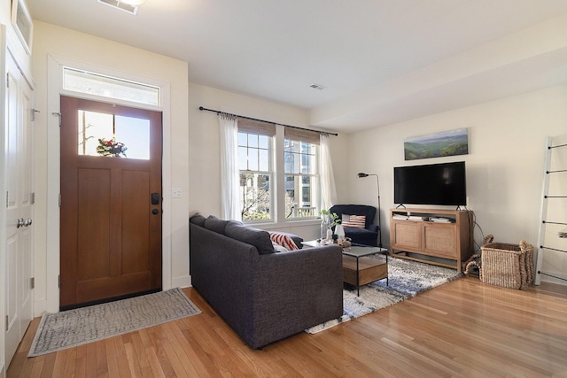 living area with light wood-style floors and visible vents