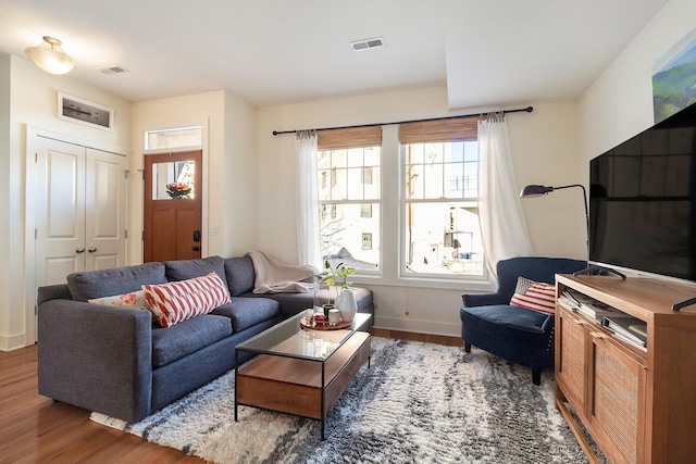 living area with visible vents, baseboards, and wood finished floors