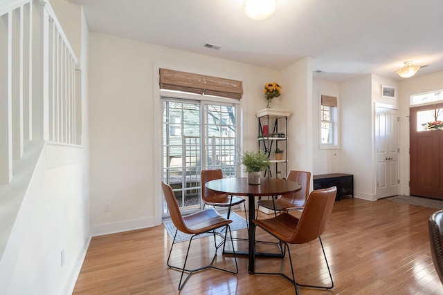 dining space with light wood-type flooring, visible vents, and baseboards