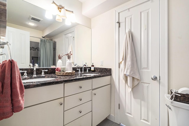 full bath featuring double vanity, curtained shower, visible vents, and a sink