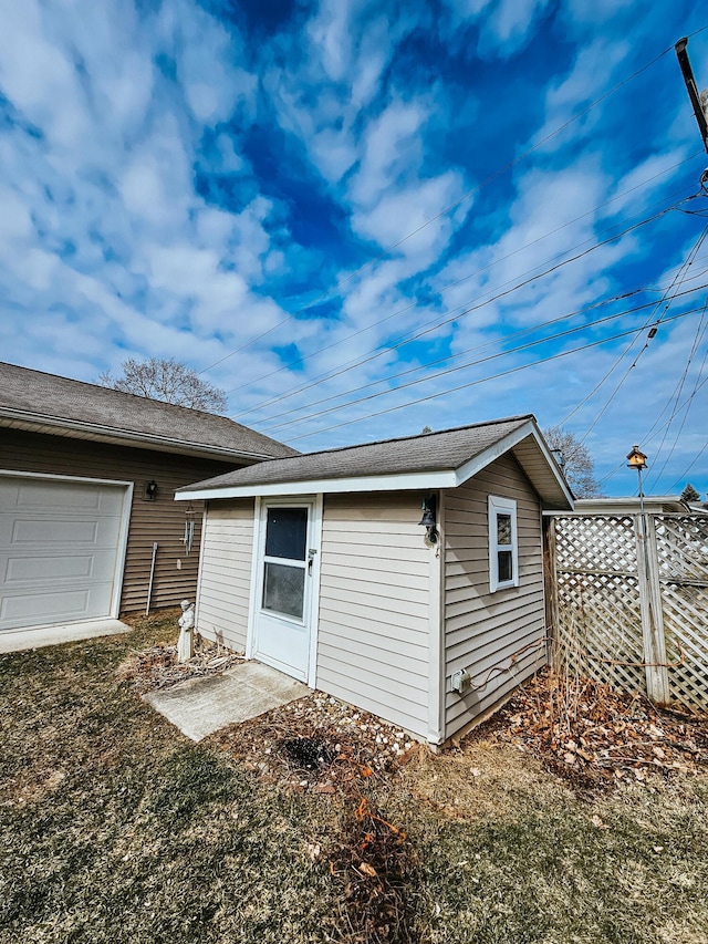 back of property featuring fence and an outdoor structure