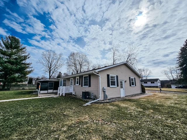 view of front of house featuring cooling unit, a sunroom, and a front yard