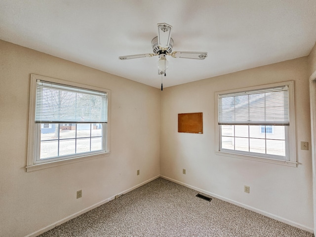 empty room featuring carpet floors, plenty of natural light, visible vents, and baseboards