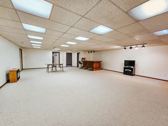 finished basement featuring rail lighting, carpet flooring, a paneled ceiling, and baseboards