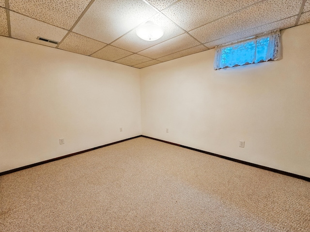 carpeted empty room featuring baseboards, visible vents, and a drop ceiling