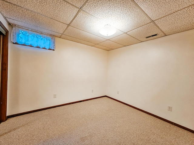 finished basement with carpet floors, a paneled ceiling, visible vents, and baseboards