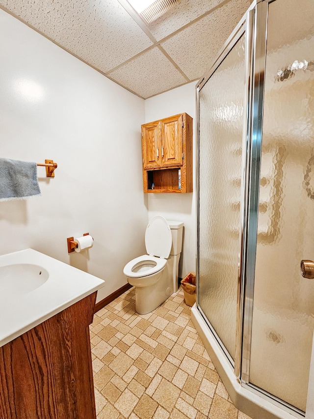 full bath featuring a paneled ceiling, toilet, a shower stall, vanity, and baseboards