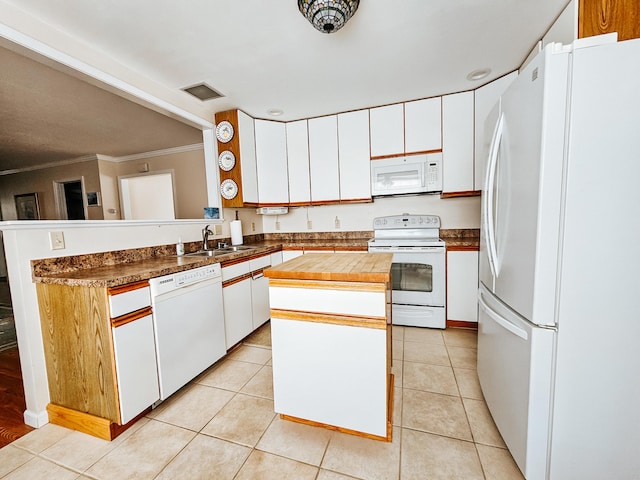 kitchen with a kitchen island, white appliances, a sink, and light tile patterned floors