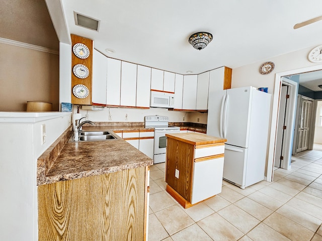 kitchen with light tile patterned floors, butcher block counters, a kitchen island, a sink, and white appliances