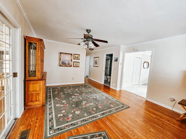 interior space with visible vents, crown molding, baseboards, and wood finished floors