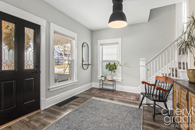 entryway featuring baseboards, stairs, visible vents, and wood finished floors