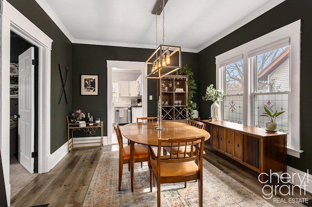 dining room with dark wood-type flooring, crown molding, and baseboards