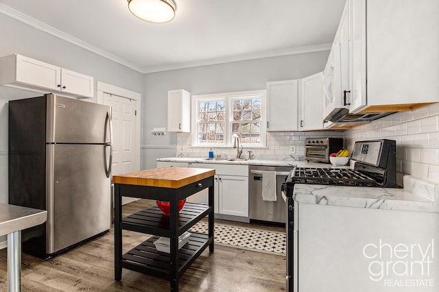 kitchen with appliances with stainless steel finishes, white cabinetry, crown molding, and decorative backsplash