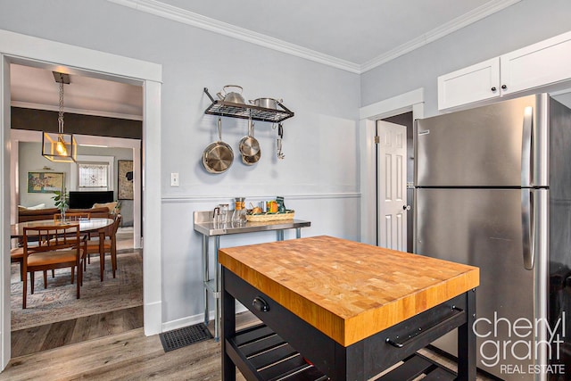 kitchen featuring wood finished floors, freestanding refrigerator, crown molding, white cabinetry, and wooden counters