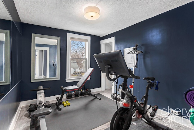 exercise area with baseboards and a textured ceiling