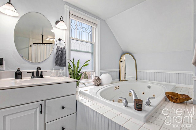 full bath with a wainscoted wall, lofted ceiling, curtained shower, vanity, and a jetted tub