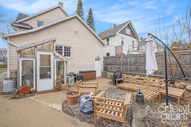 rear view of property featuring a patio area, fence, and a chimney