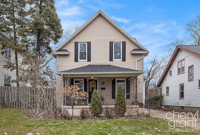 view of front of property featuring covered porch, fence, and a front lawn