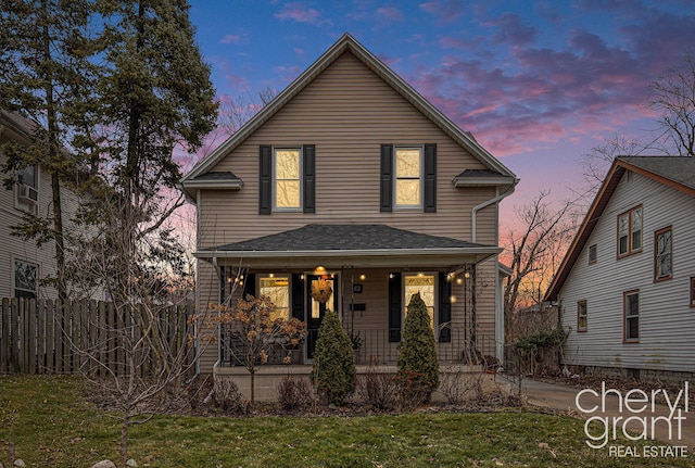 view of front of home with covered porch, fence, a lawn, and roof with shingles