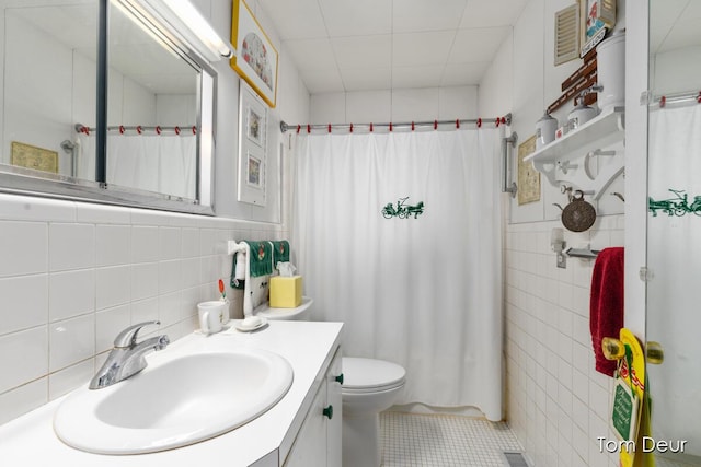 full bathroom featuring toilet, vanity, tile walls, a shower with curtain, and tile patterned floors