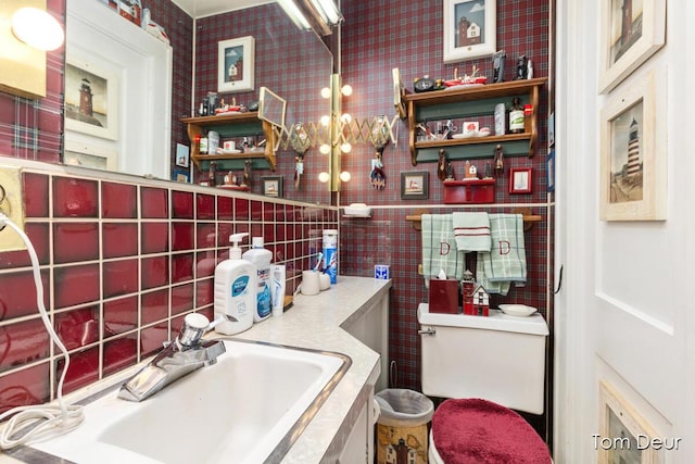 bathroom with a sink, toilet, and decorative backsplash