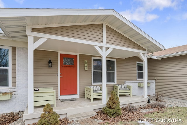 entrance to property featuring covered porch and brick siding