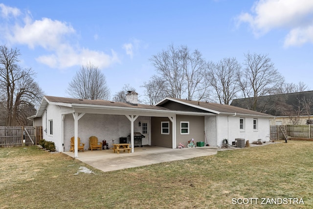 rear view of house with a patio, cooling unit, brick siding, fence, and a lawn