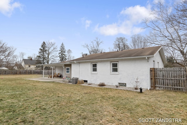 back of house with brick siding, a patio, a fenced backyard, and a lawn