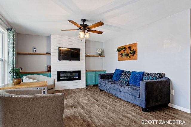 living area with a fireplace, wood finished floors, a ceiling fan, and baseboards