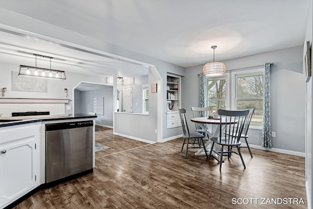 dining space with dark wood-style floors, arched walkways, and baseboards