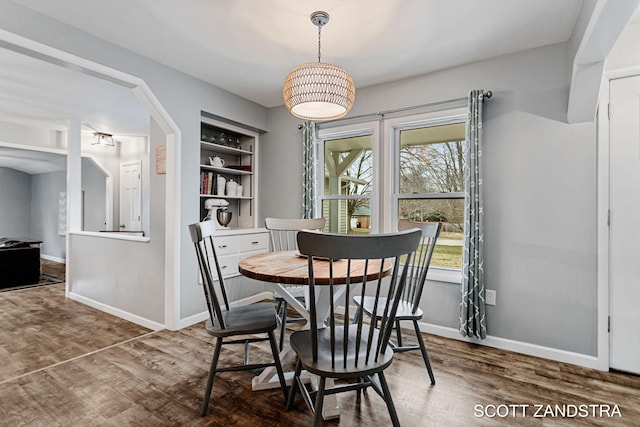 dining space with built in features, baseboards, and wood finished floors