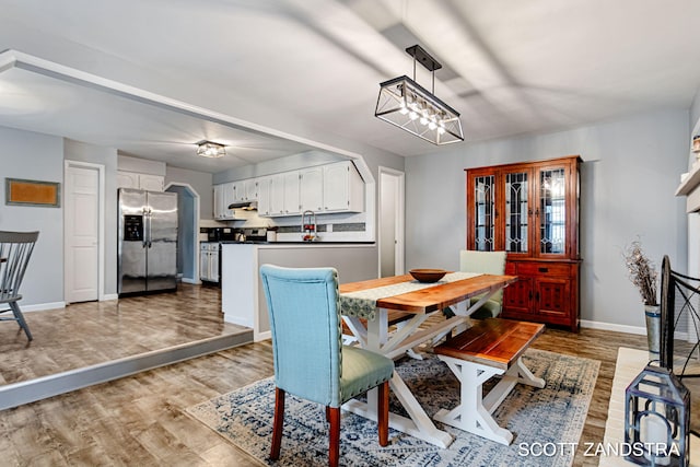 dining space with baseboards and light wood finished floors