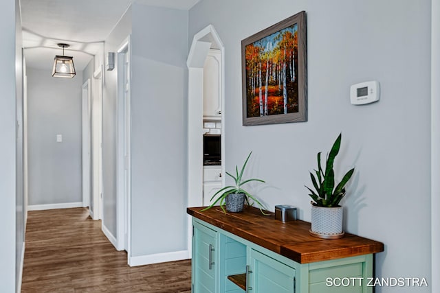 hallway with dark wood-style floors and baseboards