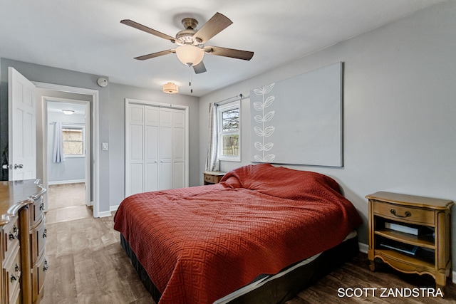 bedroom featuring a ceiling fan, a closet, baseboards, and wood finished floors