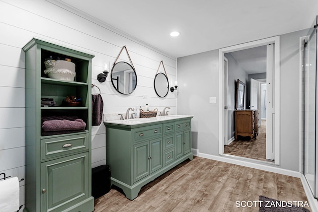 bathroom featuring double vanity, a sink, baseboards, and wood finished floors